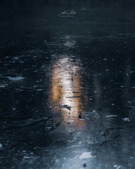 Reflexion von Licht auf einer gefrorenen, dunklen Oberfläche.